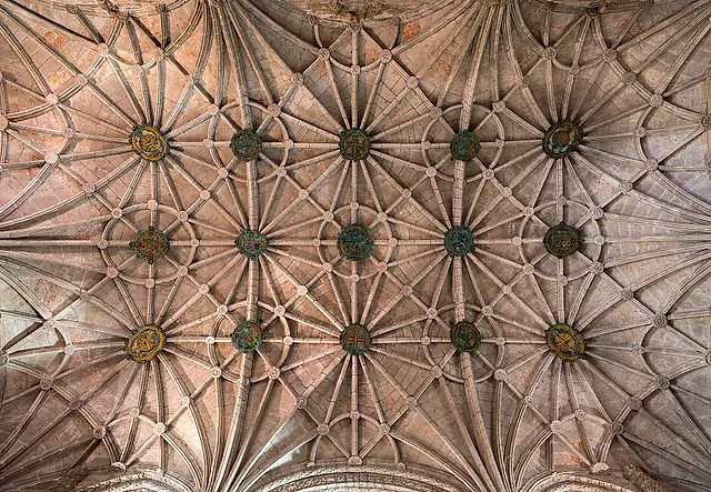 Looking straight up at the star-shaped ribbed vault of the church, with round decorated bosses where the ribs meet